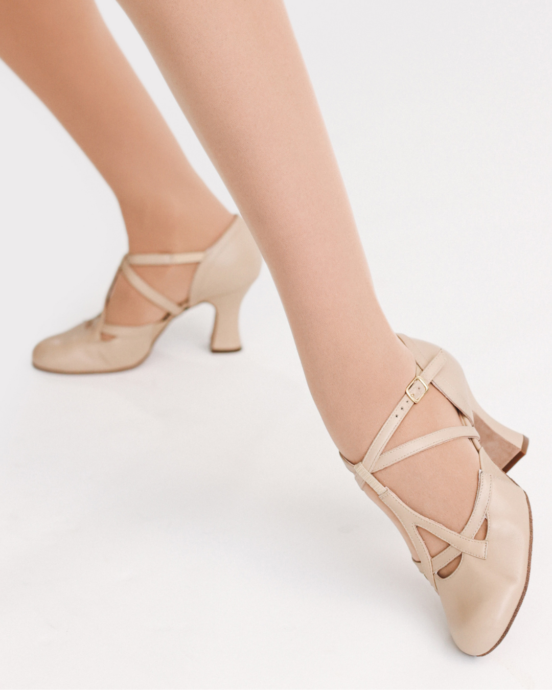 Beige high-heeled shoes worn by a person on a light background