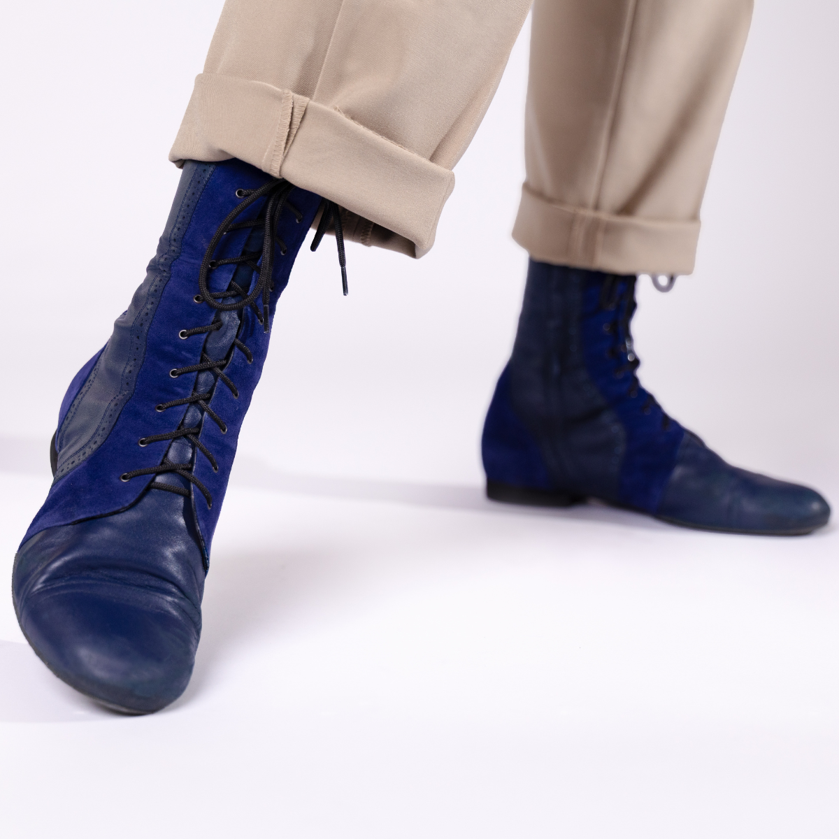 Blue leather shoes worn with beige pants on a white background
