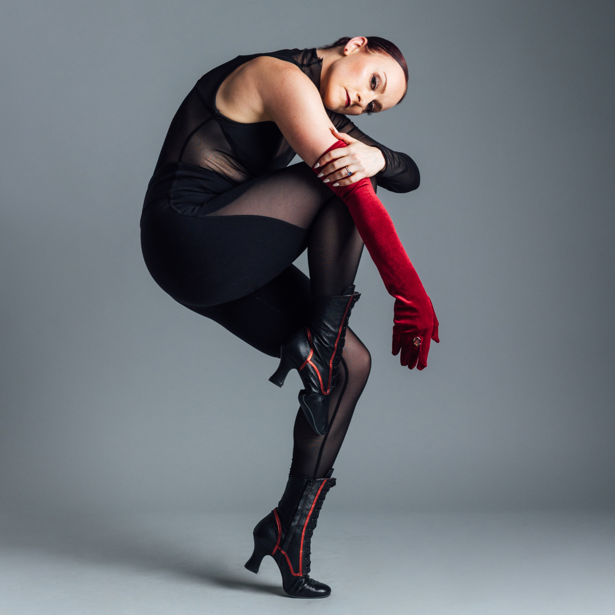 Woman in black outfit with LaDuca Shoes on posing against a gray background